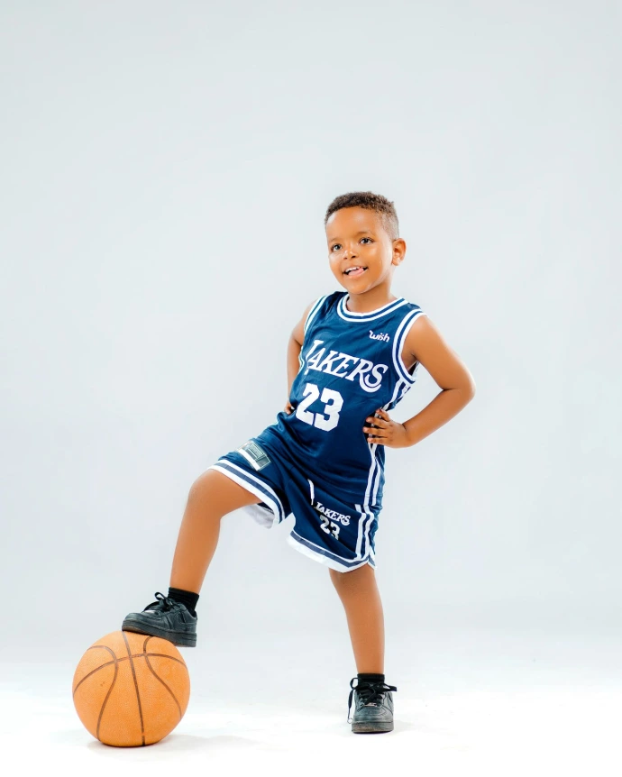 A young boy in a basketball uniform holding a basketball